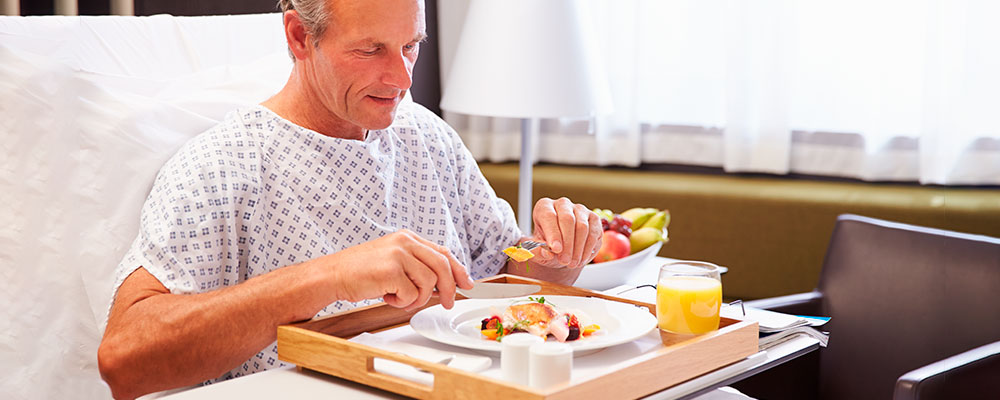 A hospital patient eating breakfast with a glass of juice