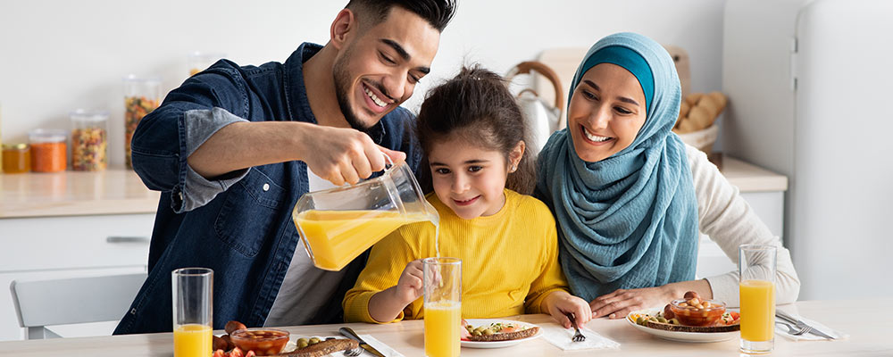 A happy family sitting down to breakfast with orange juice