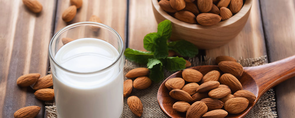 A glass of almond milk with almonds on the table